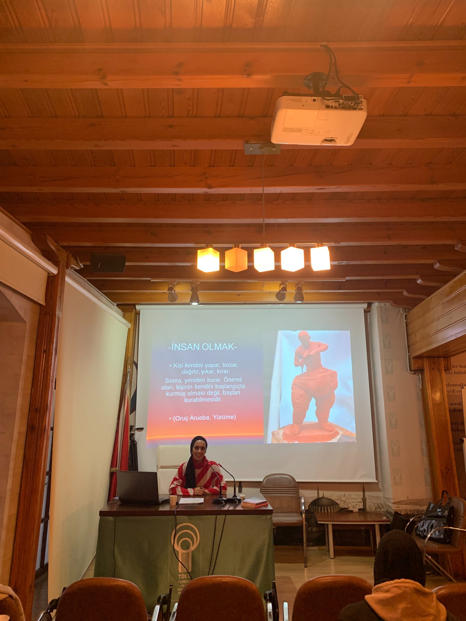 Psikolog Beyza Türkmen sunum yapıyor — TDED ahşap salonlu konferans